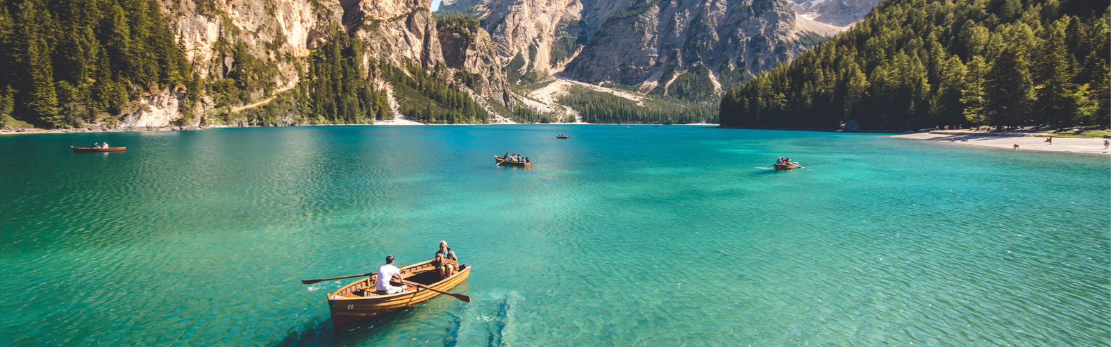 Two people on a rowboat with mountains in the background