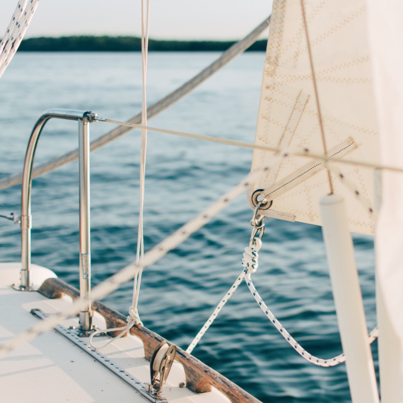 The sails of a boat with the ocean in the background